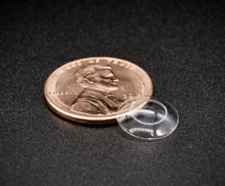 A penny sitting on top of a table next to a glass object.